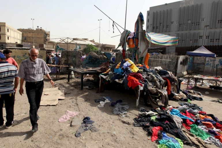 A man walk past clothes scattered at the site of a suicide bomb attack in Baghdad