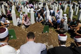 People sit around graves and tombstones at the Memorial Center Potocari, near Srebrenica