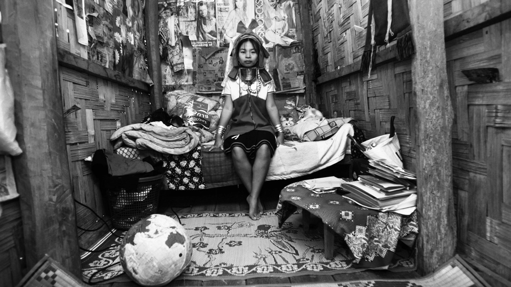 Zember sits in her hut in the village of Nai Soi in northern Thailand. The plastic globe is one of her most treasured possessions, and the walls are plastered with magazine covers of women in skimpy outfits, including her idol, Britney Spears [Jack Picone] 