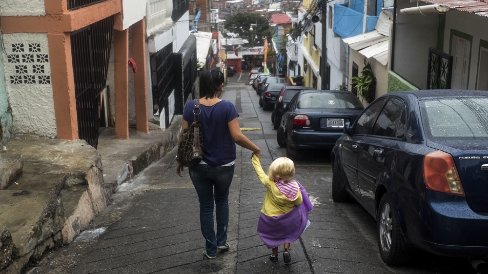 Mother and daughter navigate the slum where they live on their way to daycare for Sofia and work for Carla [Santi Donaire/Al Jazeera] 