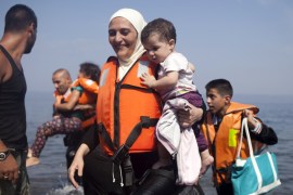 A Syrian refugee holds a child moments after arriving on a dinghy on the Greek island of Lesbos [REUTERS]