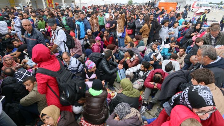 Migrants wait to board b