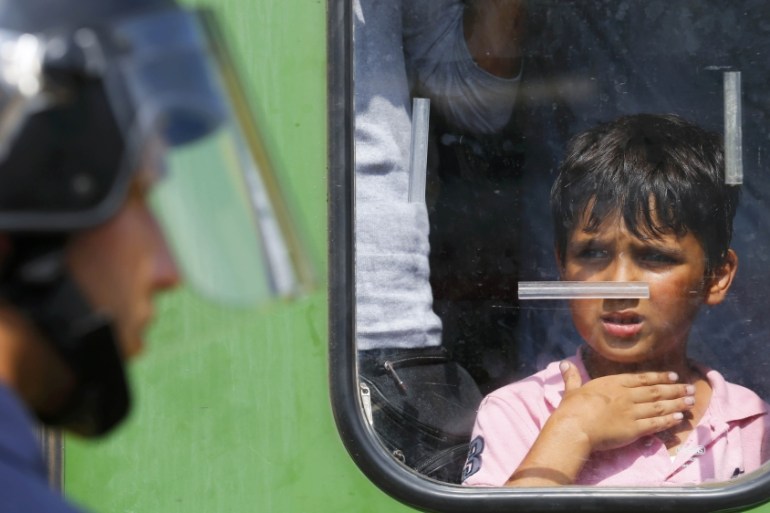 A migrant boy looks at a Hungarian policeman at the railway station in the town of Bicske