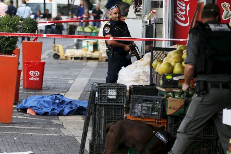 Israeli police stand next to the body of a dead Palestinian assailant at the spot where he stabbed two Israeli Jews before he was shot dead outside Jerusalem''s Old City