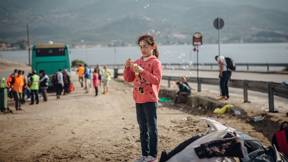 Ten-year-old Jala from Syria blows bubbles at the Oxi camp, set up by McRostie on the island of Lesbos, Greece. [Andrea DiCenzo/ Al Jazeera]