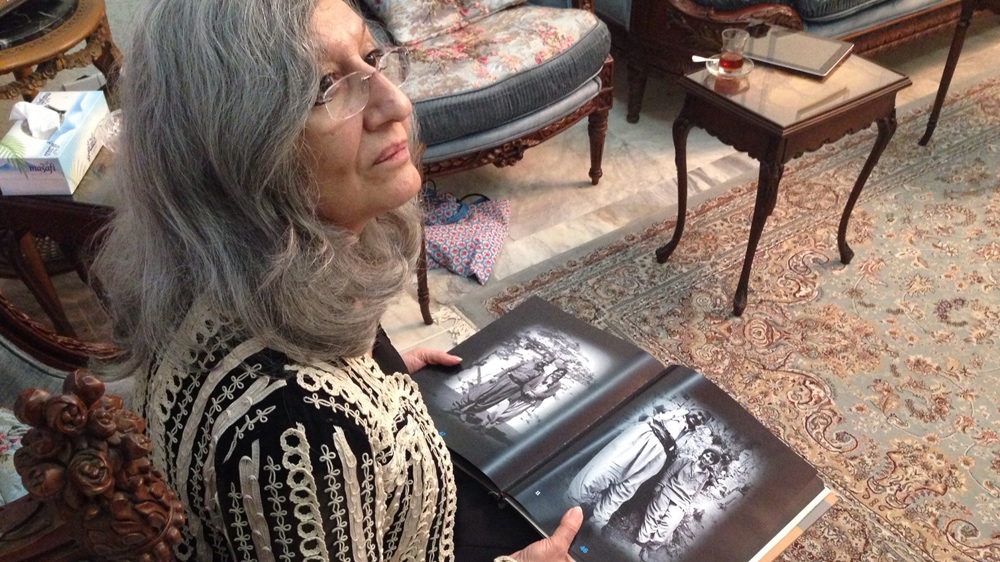 Hero, at her home in Sulaimania, looks through a book of archival photographs [Lara Fatah/Al Jazeera]