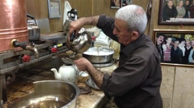 Bakr Hama Sharif, owner of the Chaikhana Shaab, pours tea for his customers [Lara Fatah/Al Jazeera]