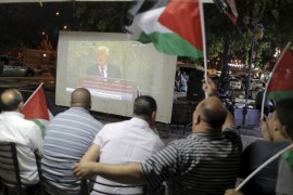 Palestinians wave Palestinian flags as they watch on a large screen the speech of Palestinian President Mahmoud Abbas near Damascus Gate, outside Jerusalem''s Old City