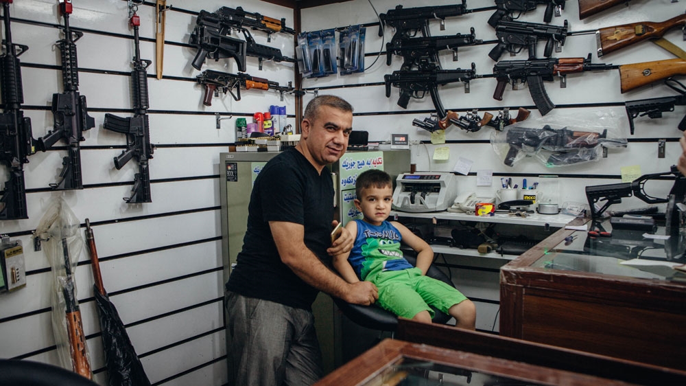 Kamal Mahmood and his son behind the counter of their family shop [Andrea DiCenzo/Al Jazeera]