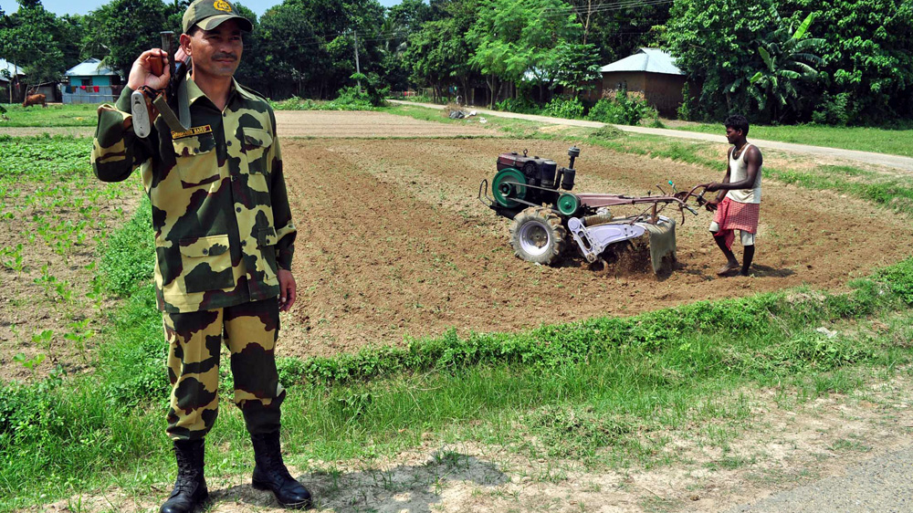 Indian border guards patrol a divided village as a farmer cultivates his land [Pinaki Das/Al Jazeera] [Al Jazeera]