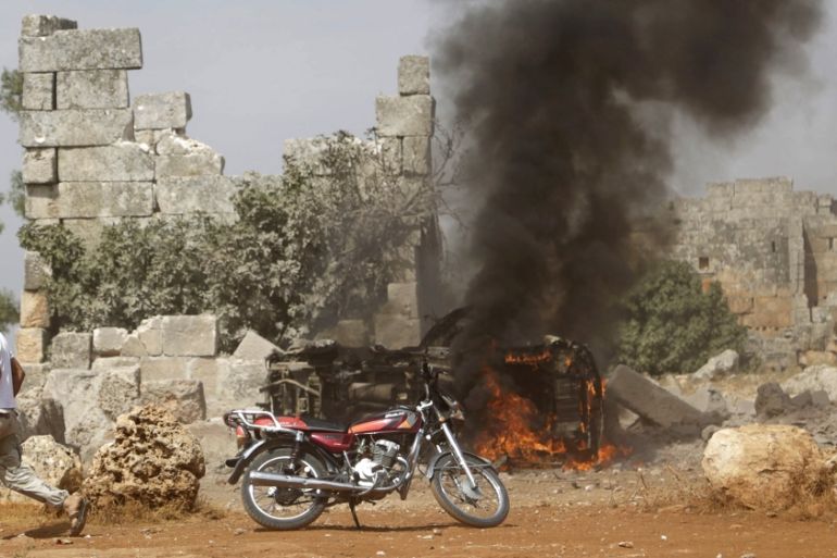A man runs past a burning military vehicle at a base controlled by rebel fighters from the Ahrar al-Sham Movement in the southern countryside of Idlib