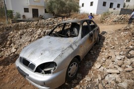 Palestinian boy looks at a car belonging to Palestinians, which residents said was burnt by alleged Jewish settlers, in Beit Ilu village near the occupied West Bank city of Ramallah