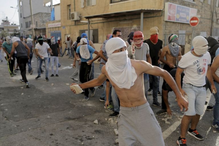 Palestinian protesters throw stones towards Israeli police during clashes in Shuafat, an Arab suburb of Jerusalem [REUTERS]
