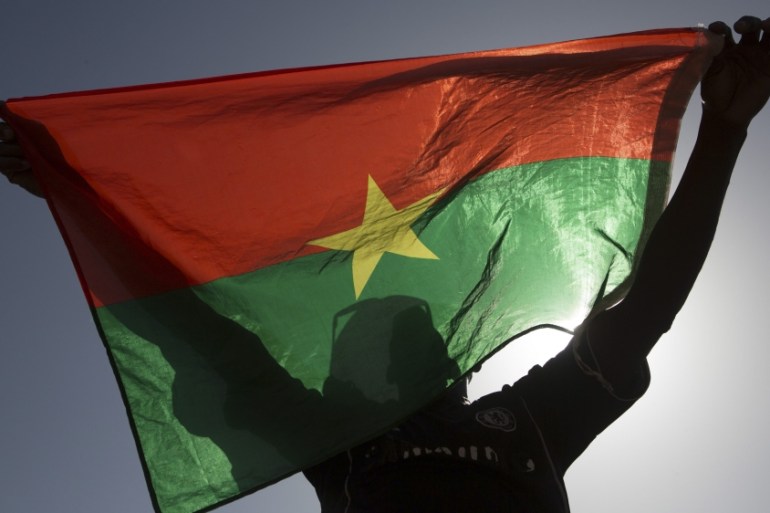 A pro-democracy protesters holds up a Burkina Faso flag at Place de la Nation in Ouagadougou