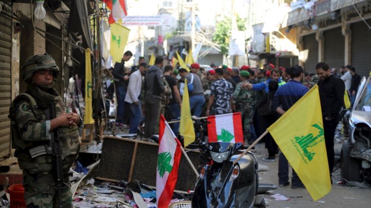 A Lebanese army soldier secures the area as Lebanese and Hezbollah flags are erected at the site of the two explosions that occured on Thursday in the southern suburbs of the Lebanese capital Beirut