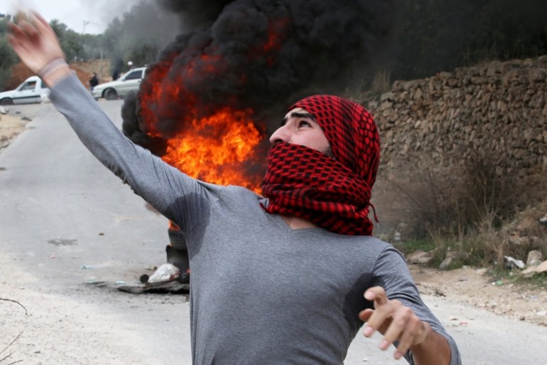 Palestinian protesters throw stones at Israeli soldiers during clashes in the West Bank city of Hebron [EPA]