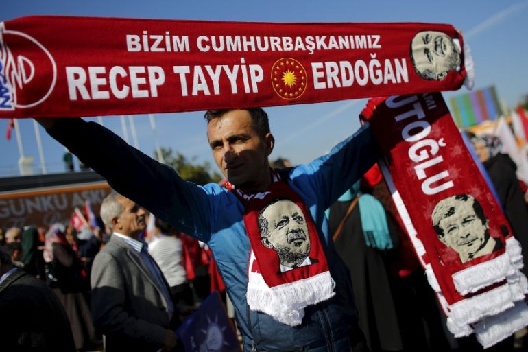 Man holds scarves bearing the names and images of Turkish Prime Minister Davutoglu and President Erdogan as supporters of the AK Party gather to wait for the arrival of Davutoglu in Istanbul