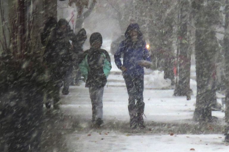 Children walking in November snow falling in Wilmette, Illinois, US