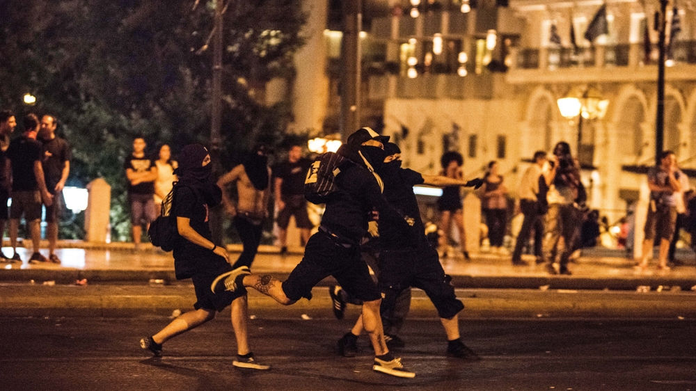 Young anarchists hurl bottles and petrol bombs at the police in central Athens [Tommy Trenchard/Al Jazeera]
