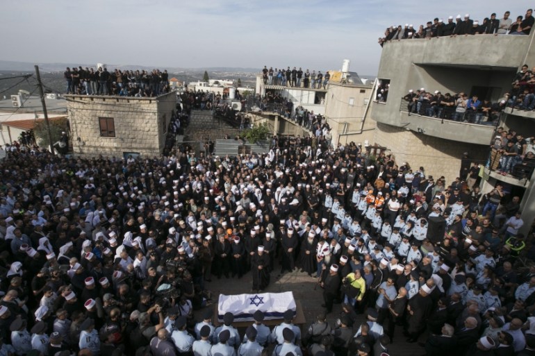 Mourners gather around the coffin of Israeli Druze police officer Zidan Nahad Seif during his funeral in Yanuh-Jat