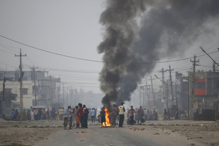 Protesters stand near burning tyres as they gather to block highway connecting Nepal and India, during general strike called by Madhesi protesters demonstrating against new constitution in Birgunj
