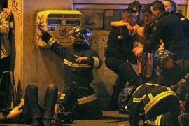 French fire brigade members aid an injured individual near the Bataclan concert hall following fatal shootings in Paris, France