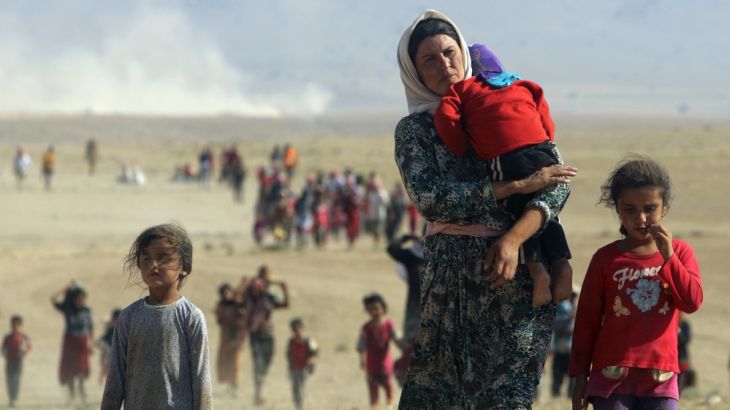Displaced people from the Yazidi minority walk towards the Syrian border