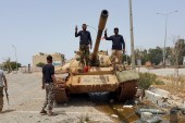 Members of the Libyan pro-government forces gesture as they stand on a tank in Benghazi, Libya, May 21, 2015. [Reuters]