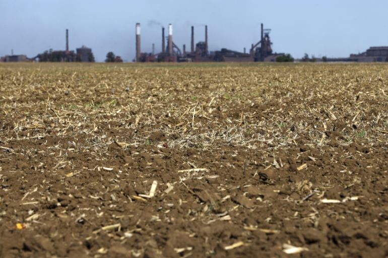 Chimneys from ArcelorMittal steel company are seen behind a dry maize field near Vanderbijlparkâ€Ž outside Johannesburg