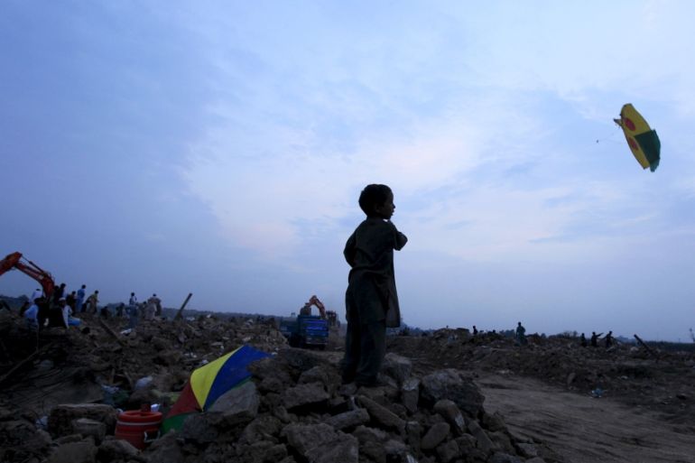 A boy flies a kite at debris of family''s house as excavator destroys neighborhood at slum on the outskirts of Islamabad
