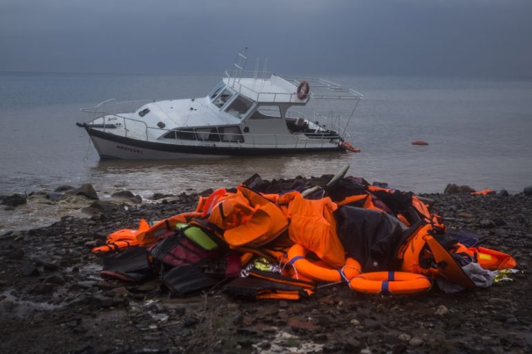 Life Jackets and a boat used by refugees and migrants to cross a part of the Aegean sea from Turkey to the Greek island of Lesbos remain on a beach