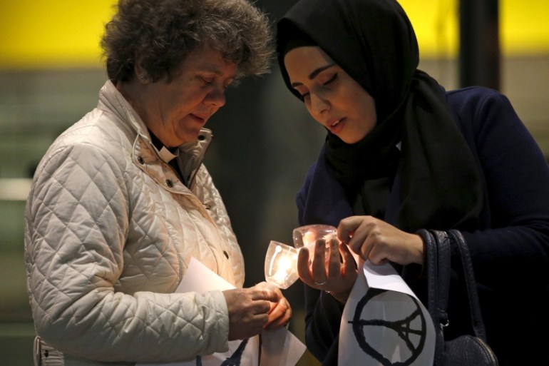 Two women light candles during an inter-faith vigil for the victims of the Paris attacks in London, Britain [REUTERS]