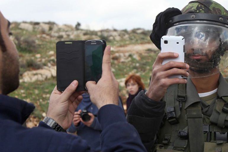 A Palestinian man and a member of the Israeli security forces take pictures of each other with their mobile phones after Palestinians from the West Bank village of Nabi Saleh, near Ramallah, demonstra