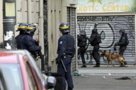 Members of special French RAID forces with a police dog and French riot police secure the area during an operation in Saint-Denis, near Paris