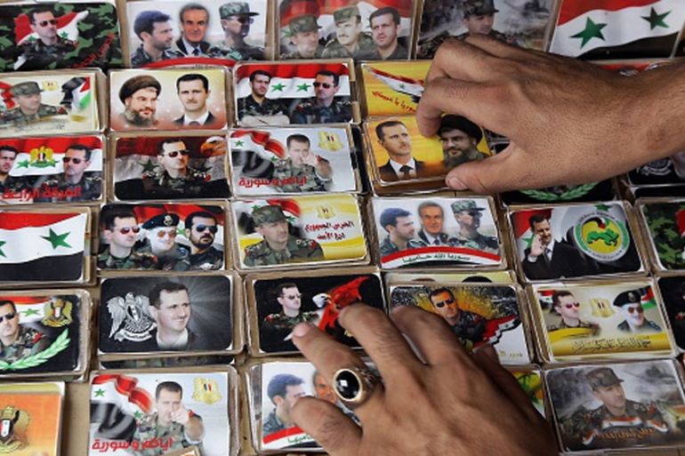 A Syrian vendor arranging pins displaying portraits of Assad with Hezbollah leader Hassan Nasrallah [Getty]