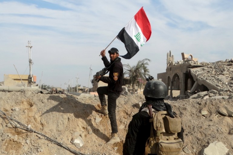 A member from the Iraqi security forces holds an Iraqi flag in the city of Ramadi