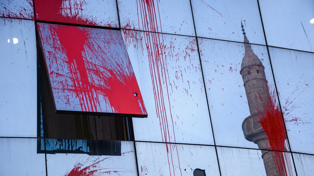 Masked protesters threw bottles of paint and damaged the windows of the Kosovo parliament building [Benas Gerdziunas/Al Jazeera] 