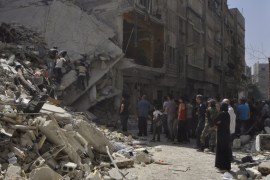 Residents inspect a site hit by what ac Yarmouk
