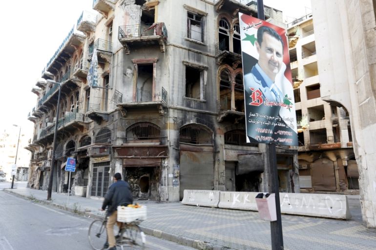 A man rides a bicycle past a poster depicting Syria''s President Bashar al-Assad near the new clock square in the old city of Homs