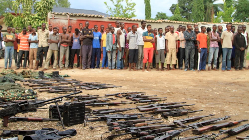Suspected fighters are paraded before the media by Burundian police near a recovered cache of weapons  [Reuters]