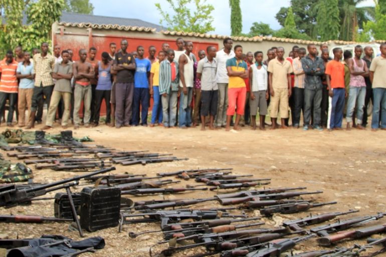 Suspected fighters are paraded before the media by Burundian police near a recovered cache of weapons after clashes in the capital Bujumbura