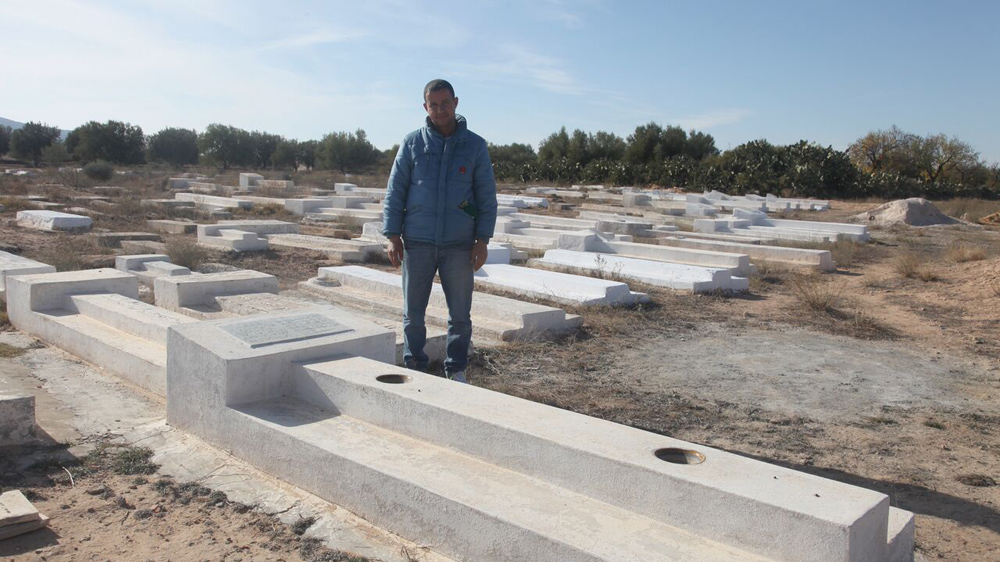 Cousin Lotfi Bouazizi, who has been unemployed for years, stands by Mohamed's grave outside Sidi Bouzid [Thessa Lageman/Al Jazeera]