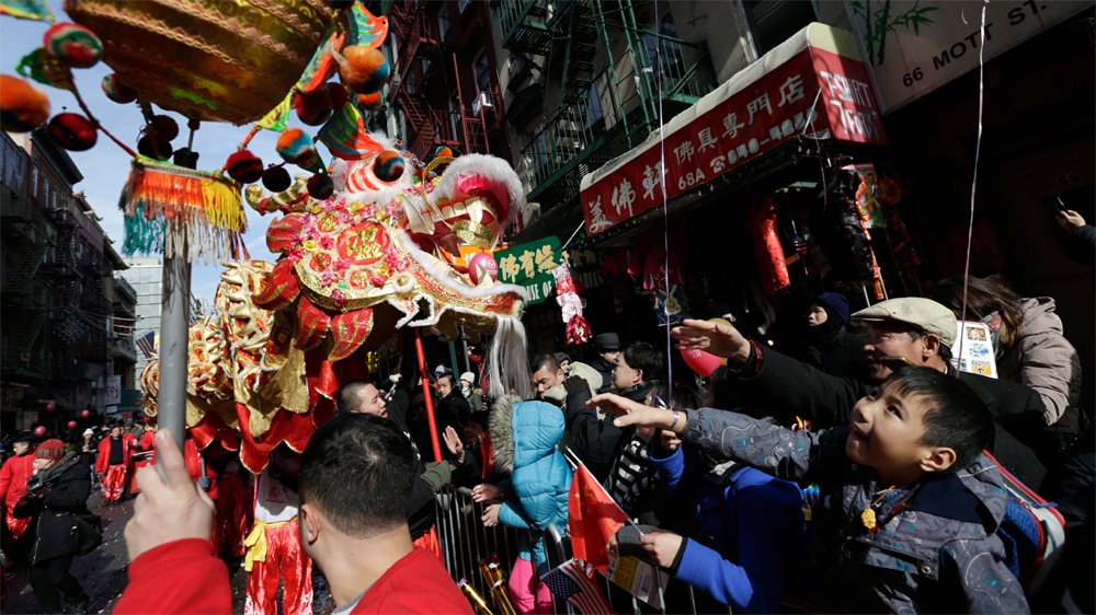 People are greeted by a dragon at the Chinese Lunar New Year parade in New York's Chinatown. Gentrification is threatening the Chinese families that once formed the tight-knit community. [EPA]