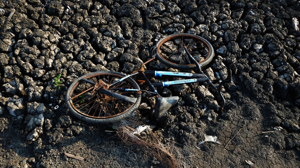 An abandoned bicycle and cracked earth at Khun Samut Chin village [Jack Picone/Al Jazeera]