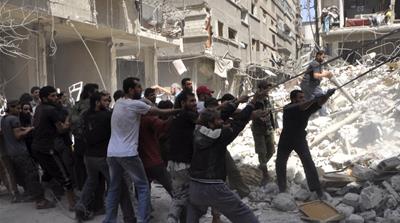 Men remove rubble at a site hit by barrel bombs in the southern outskirts of Damascus [REUTERS]
