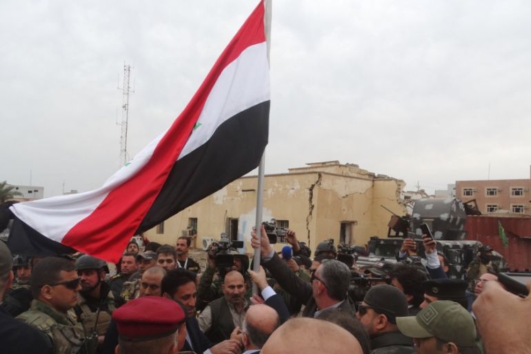 Iraqi Prime Minister Haider al-Abadi holds an Iraqi flag in the city of Ramadi