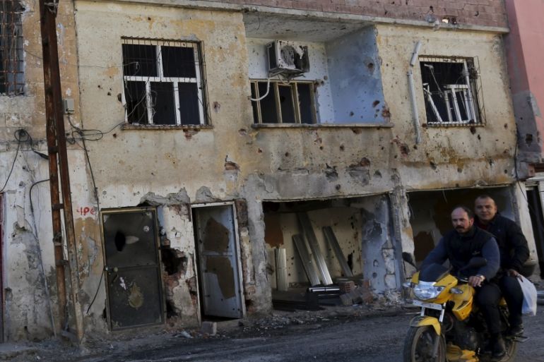 Men drive past a building which was damaged during the security operations and clashes between Turkish security forces and Kurdish militants, in the southeastern town of Silvan in Diyarbakir province,