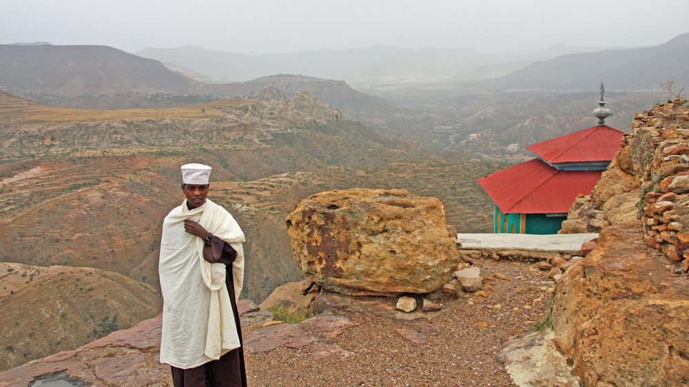 A young novice monk at Debre Damo monastery, with mountains stretching away towards the border with Eritrea [James Jeffrey/Al Jazeera] [-]