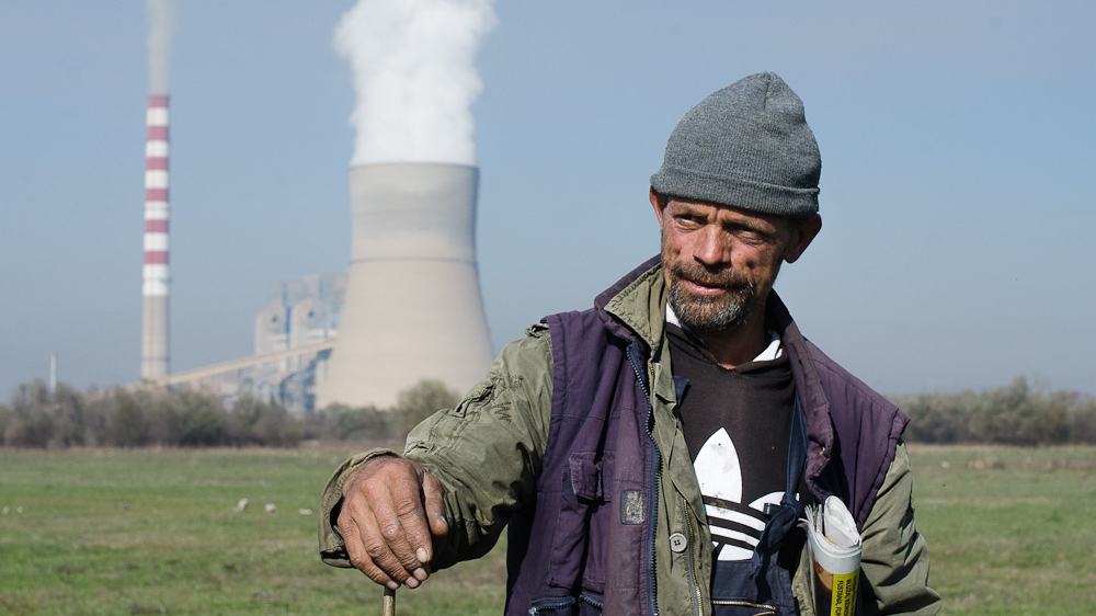 Abdurrahman Qerkezi, 45, used to work for the company that operates Kosovo’s two coal plants including Kosovo B, which is seen in the distance. Now Qerkezi herds cows, sheep and horses and says the coal plants have damaged this land. 'The environment is a catastrophe here,' he said. [Valerie Plesch/Al Jazeera]