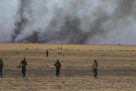 Rebel fighters walk in front of a bushfire in a rebel-controlled territory in Upper Nile State